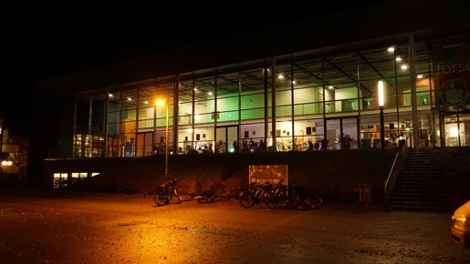 Das Audimax der Uni Lübeck bei Nacht. Das Foyer ist bunt beleuchtet.